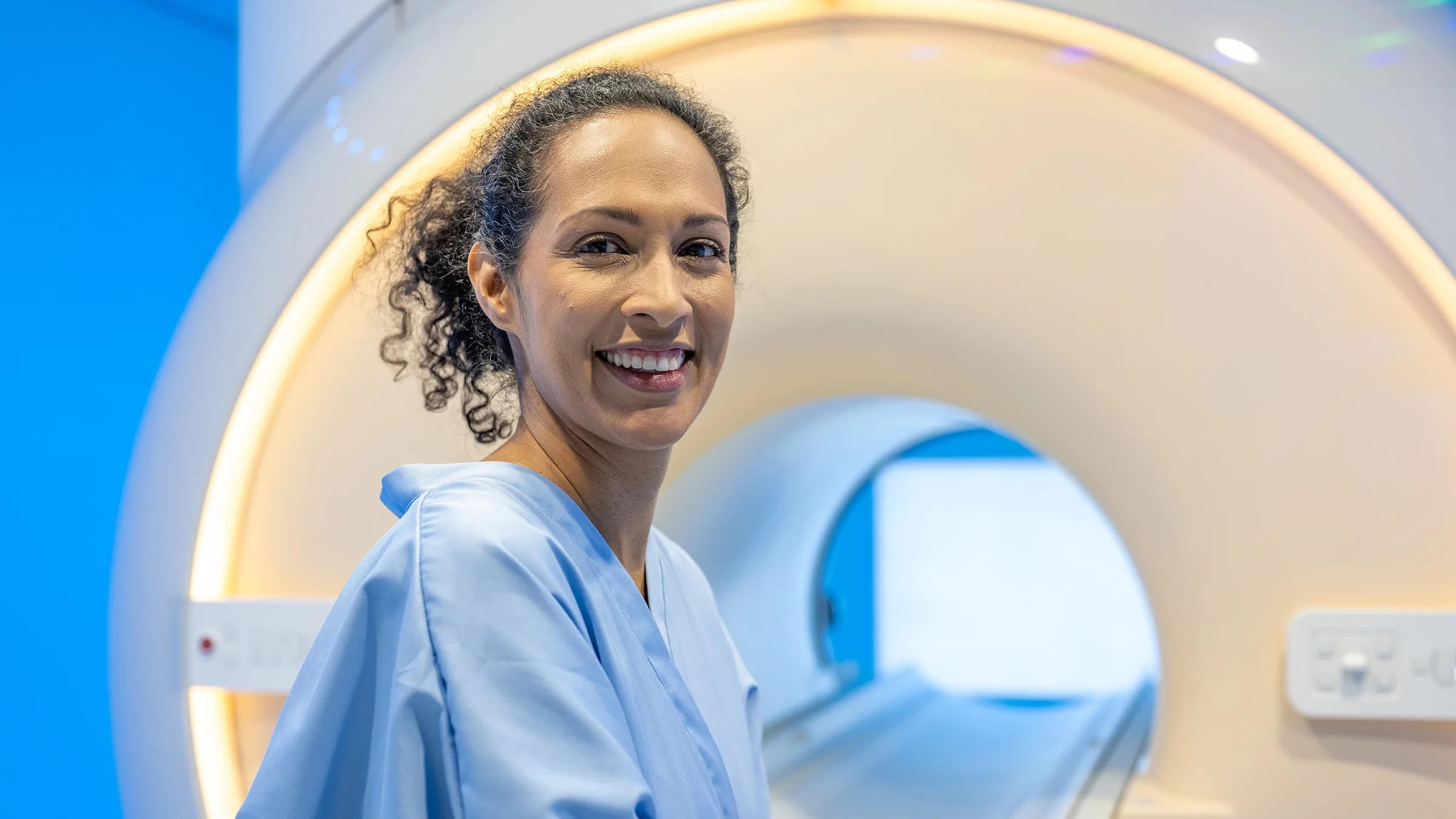 A person is sitting down in front of an MRI machine before getting a scan.