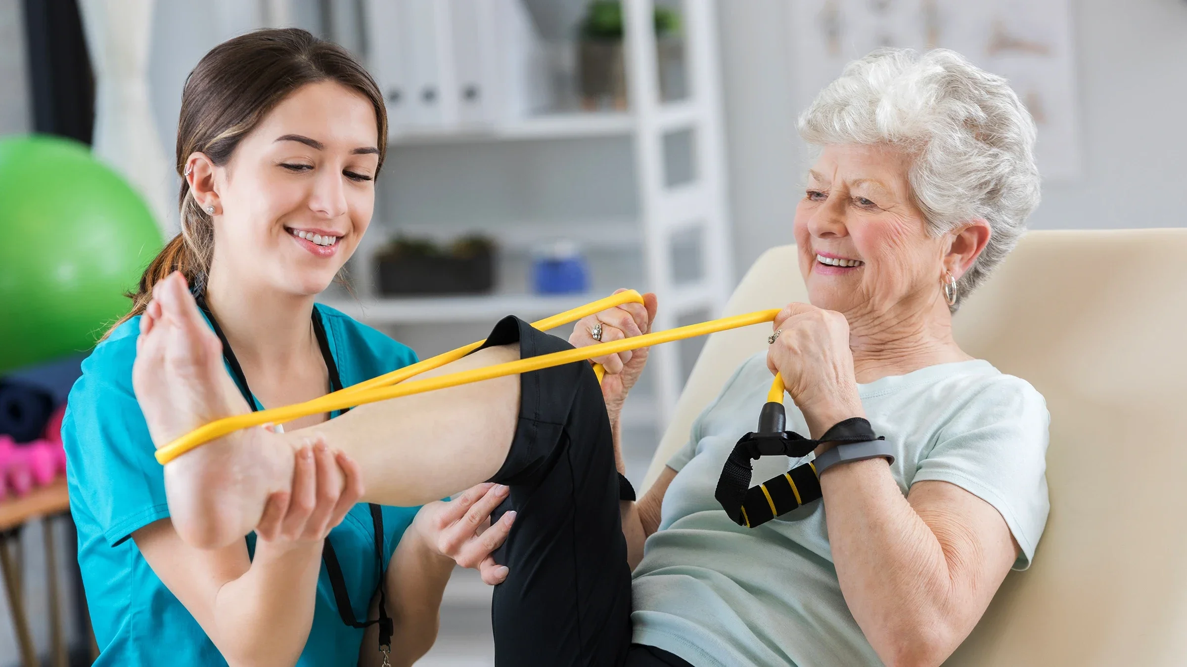 A senior woman uses a resistance band during a session with her physical therapist.
SDI Productions/E+ via Getty Images