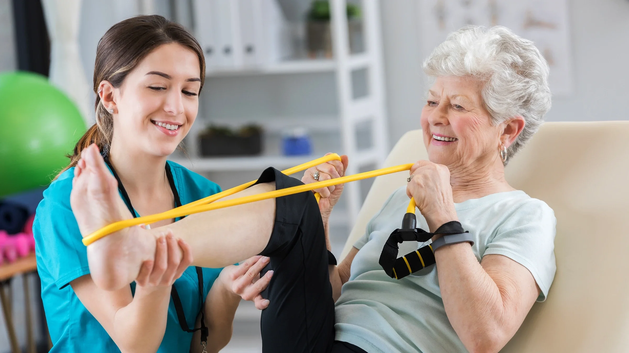 A senior woman uses a resistance band during a session with her physical therapist.