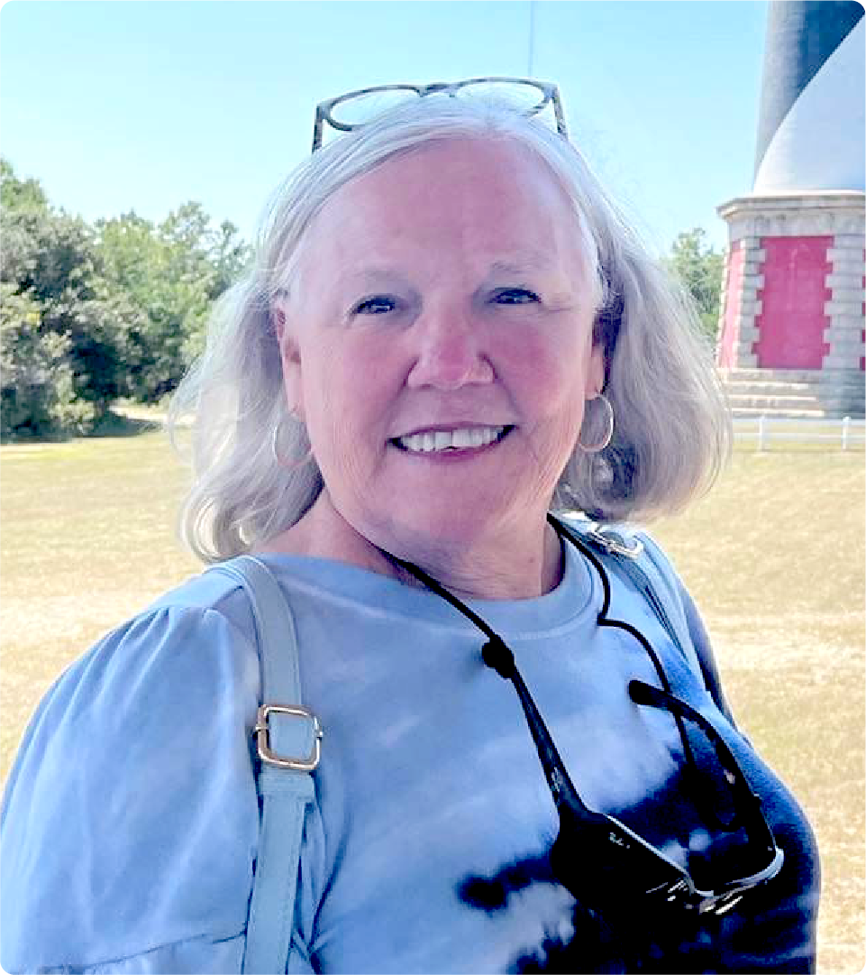 Vicki Miesbauer is pictured outdoors by a lighthouse.