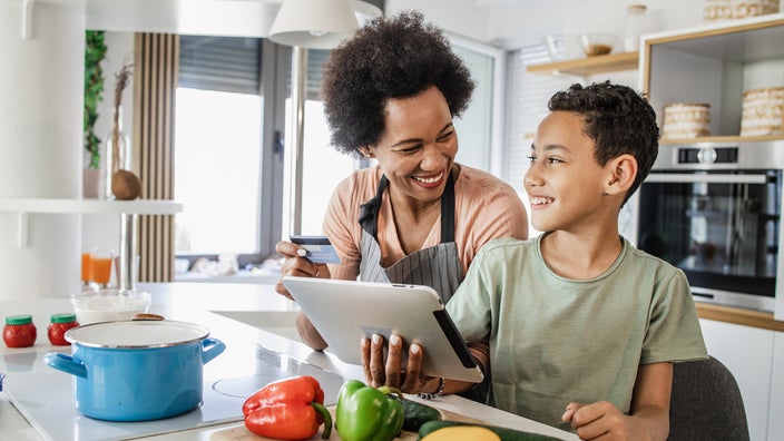 Mother and son having fun in the kitchen. They are smiling and laughing while they look at each other.
