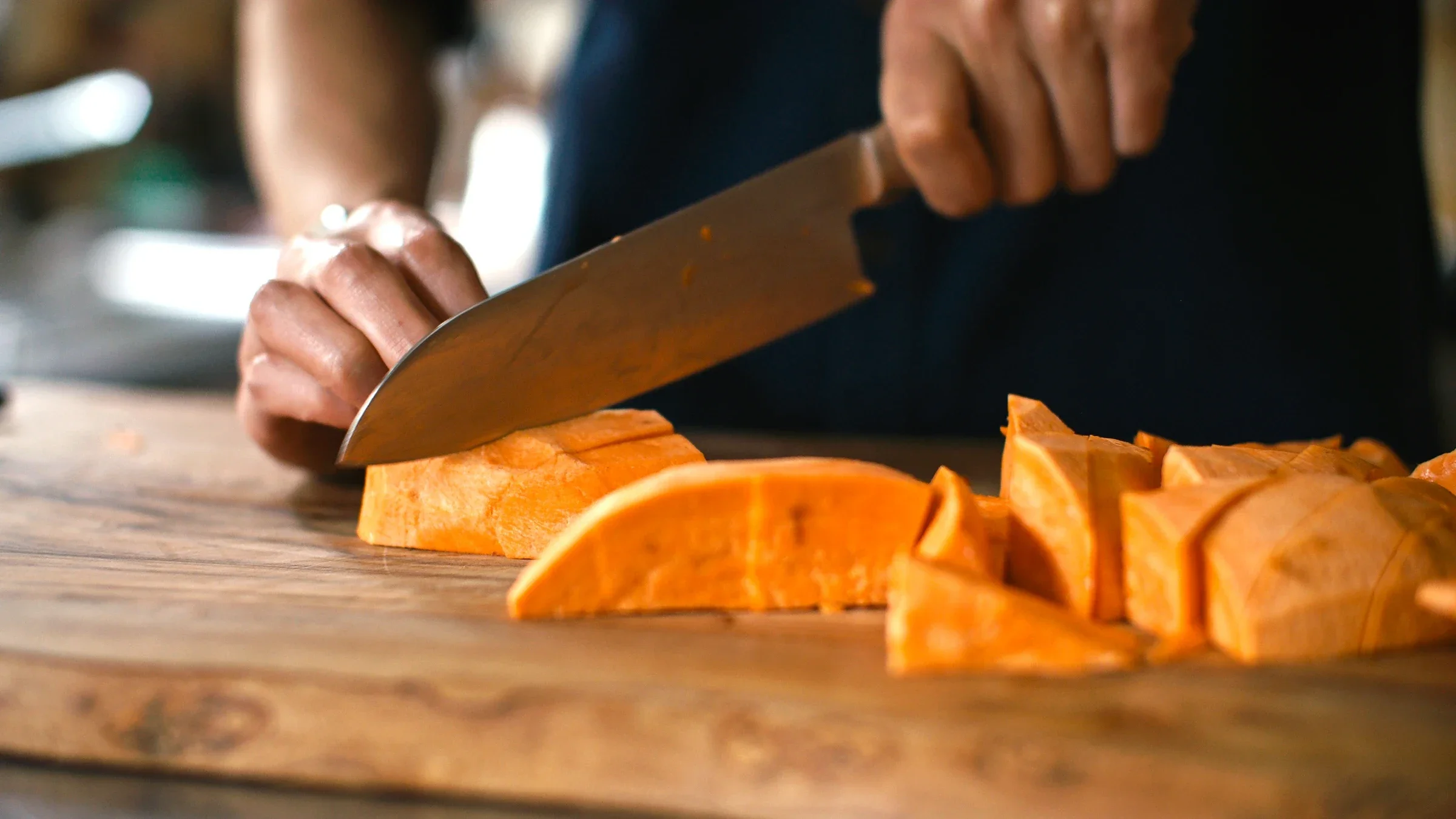 Close-up hand cutting sweet potatoes into wedges.
haoliang/E+ via Getty Images
