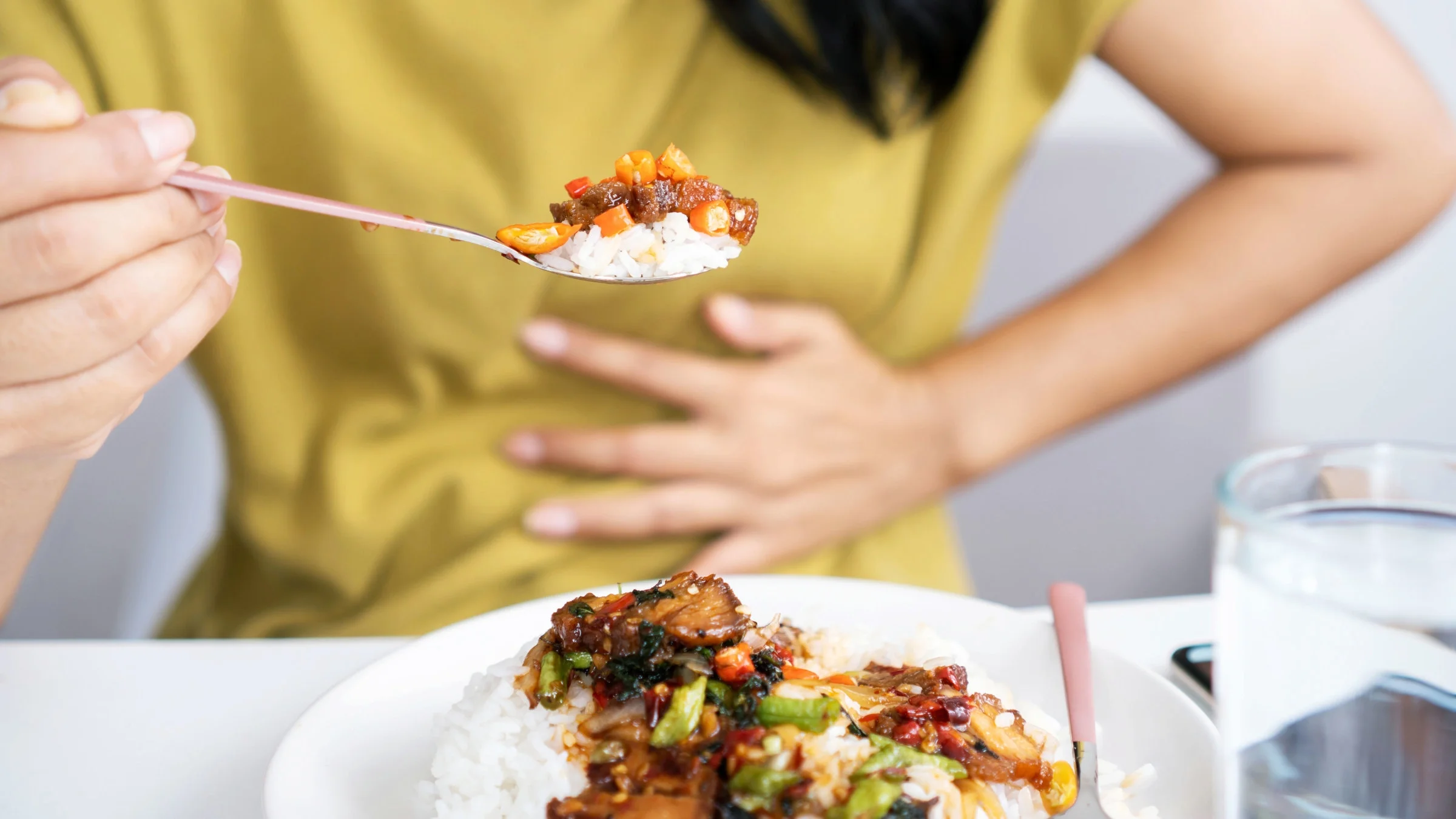 Woman eating with heartburn and close up of food.
