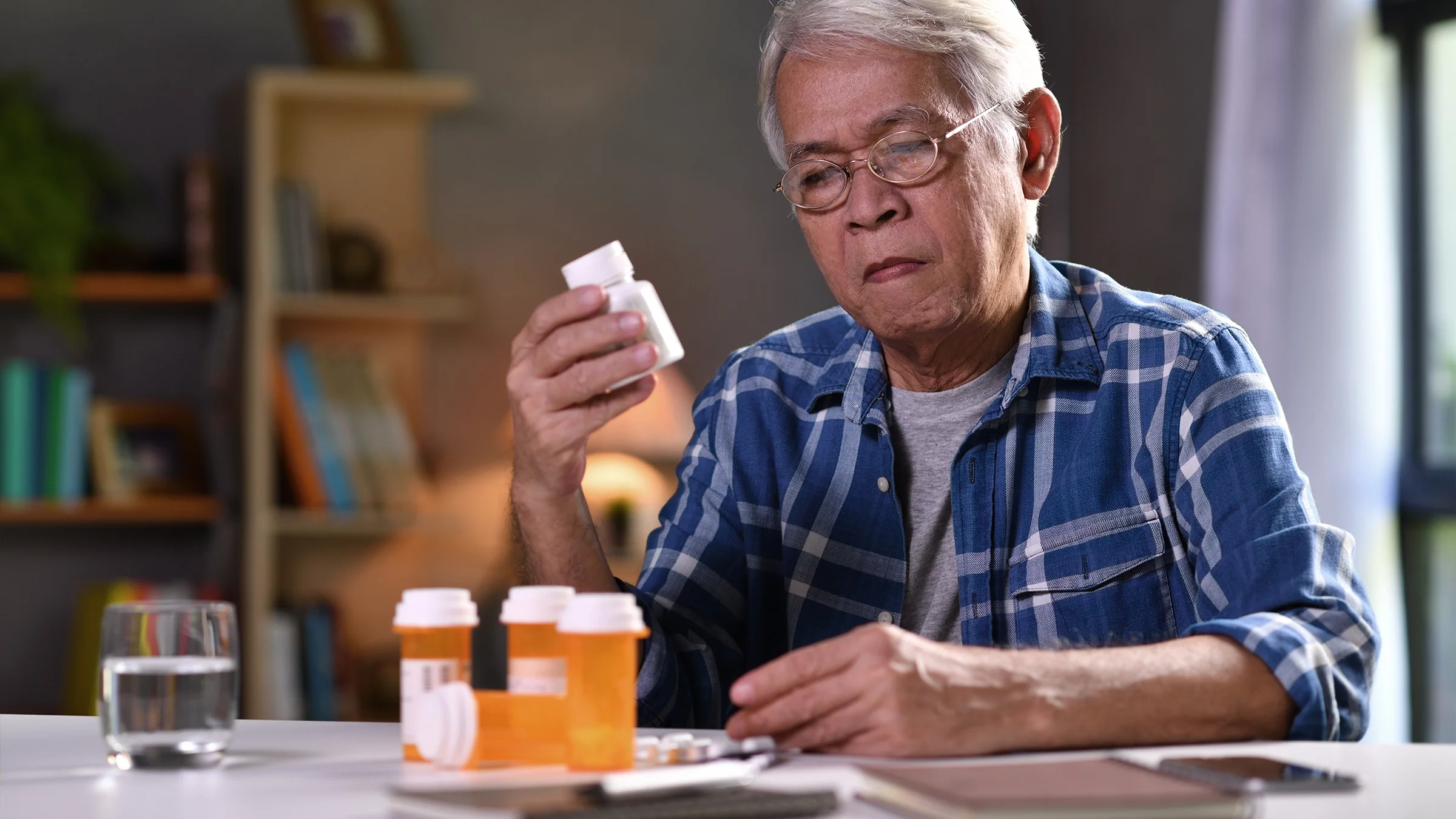 Old man reviewing his medications at the dining table.