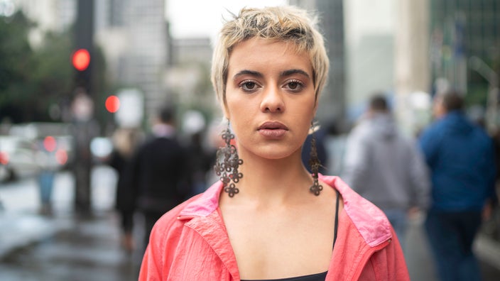 Portrait of a young queer person standing in the city streets.