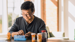 An older man uses a weekly pill organizer to organize his prescription medication.
SDI Productions/E+ via Getty Images
