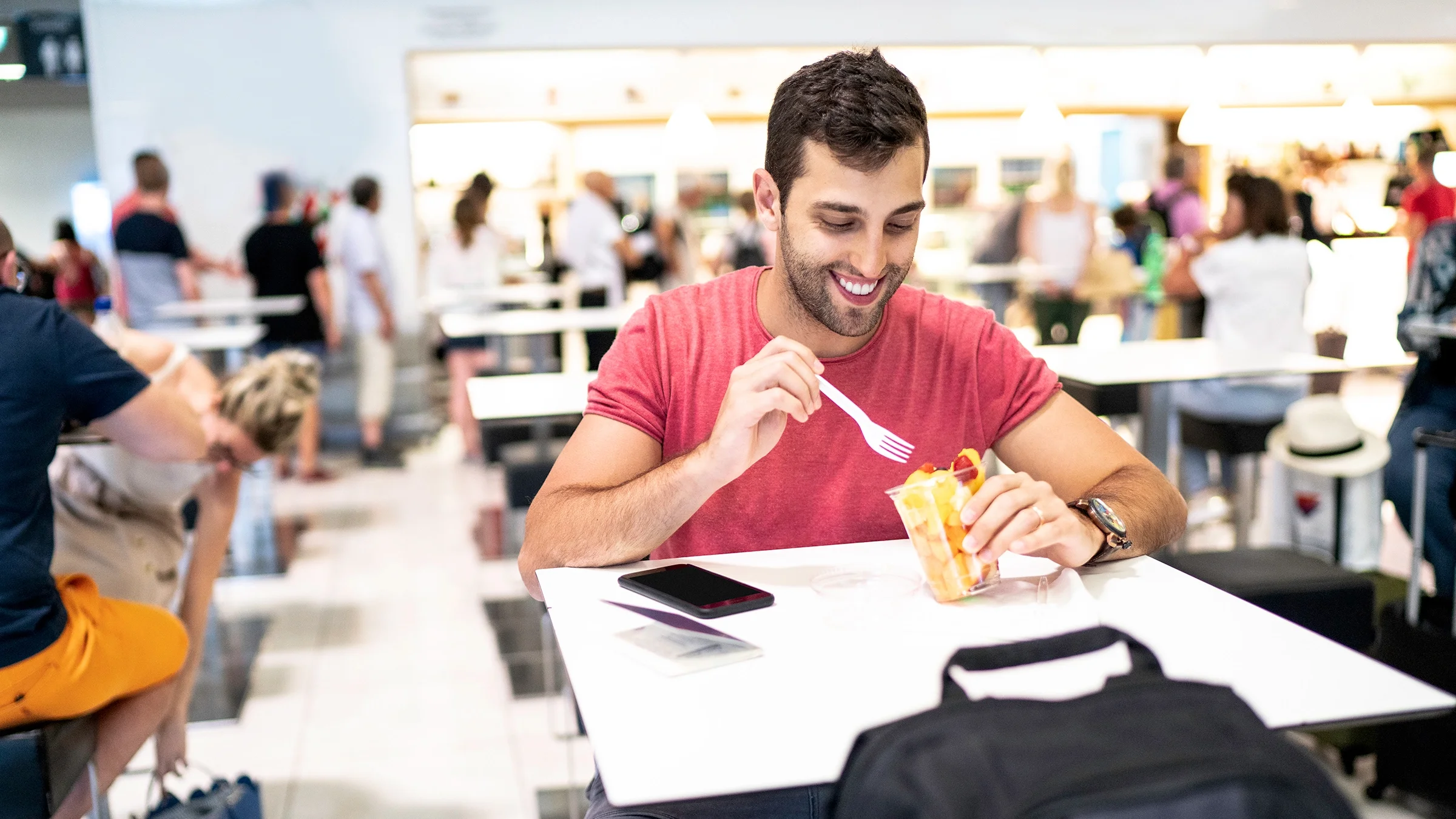 Man eating fruit in a food court.