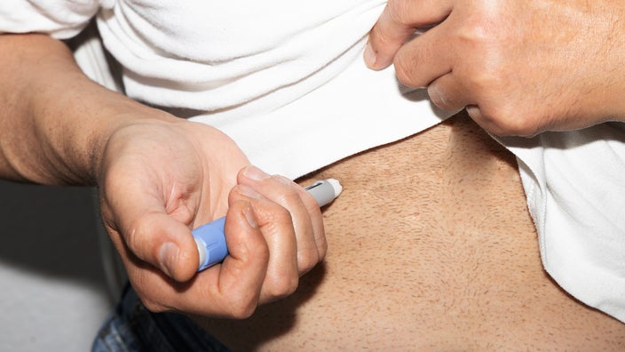 Close-up man injecting pen into stomach