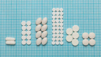 metformin: various white pills stacked on graph paper-1209819635