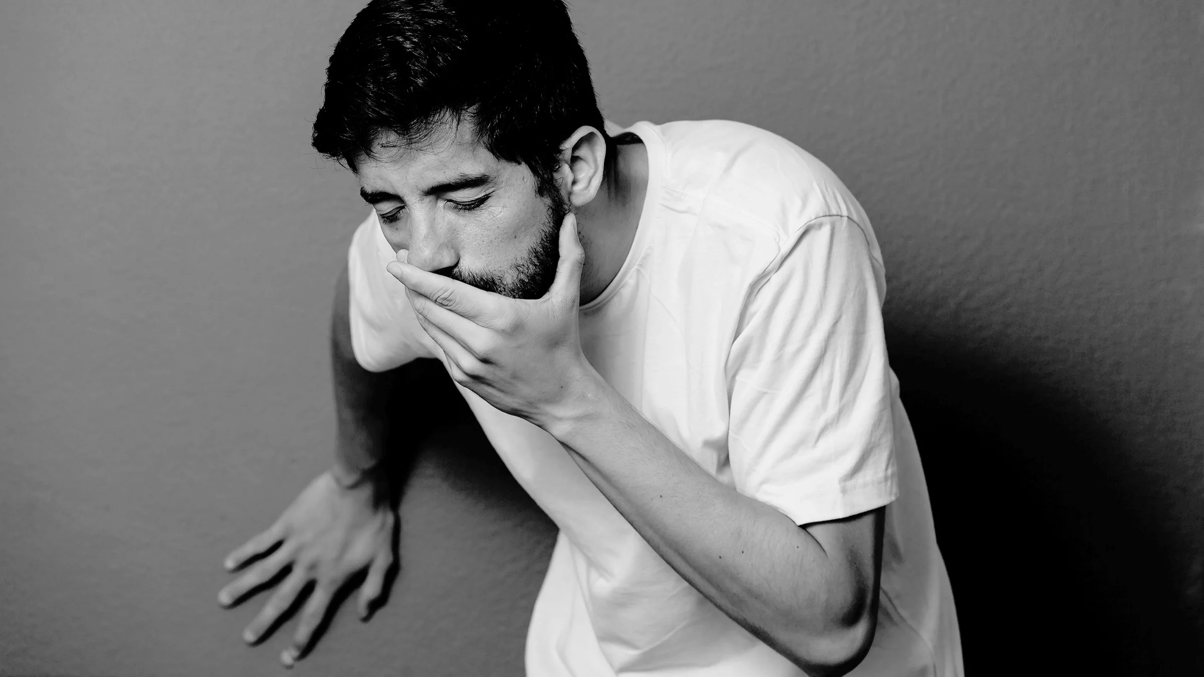 Black and white studio portrait of a man looking like he's going to throw up.