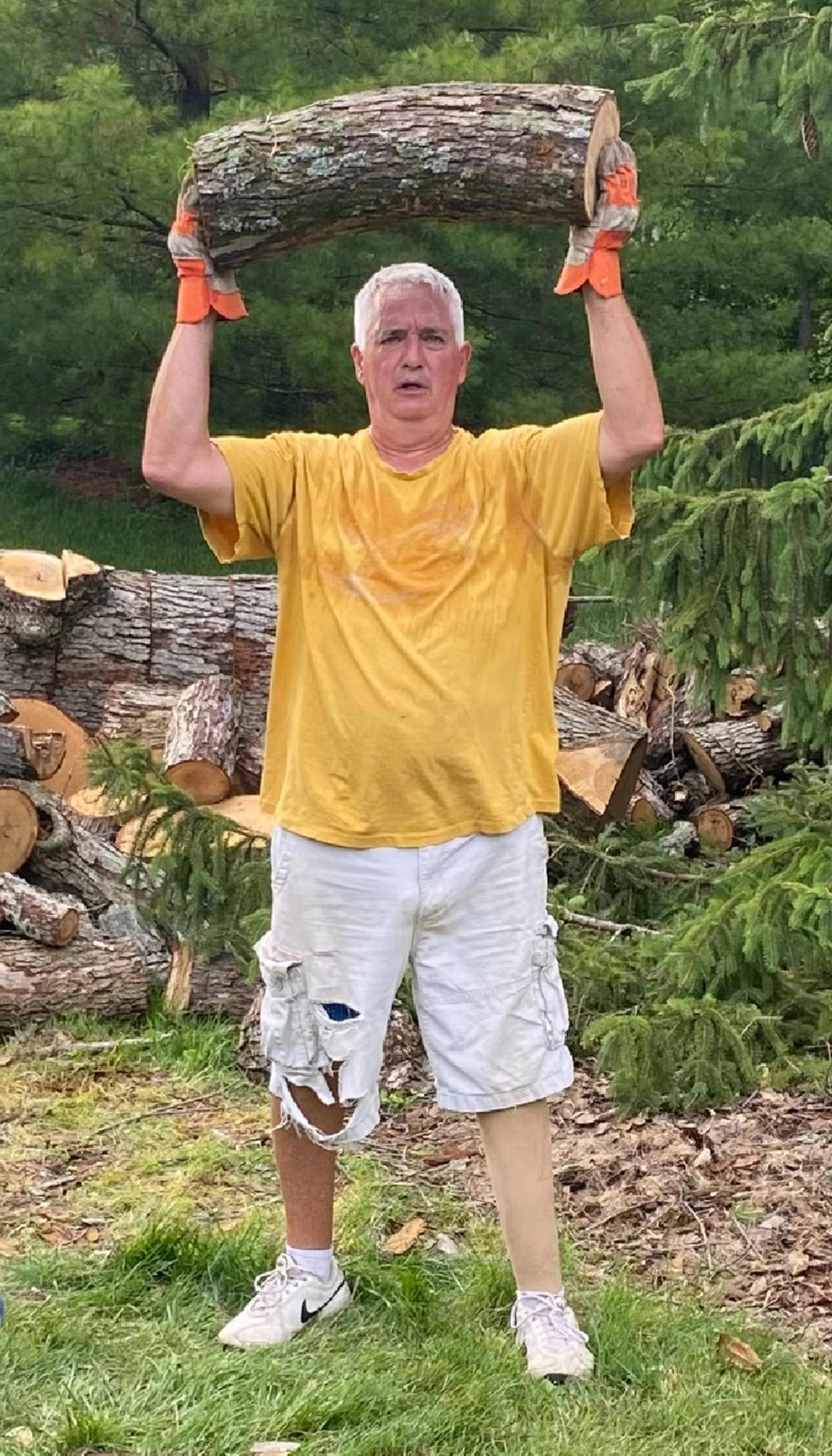Kevin Shepherd is pictured holding a log above his head while chopping wood.