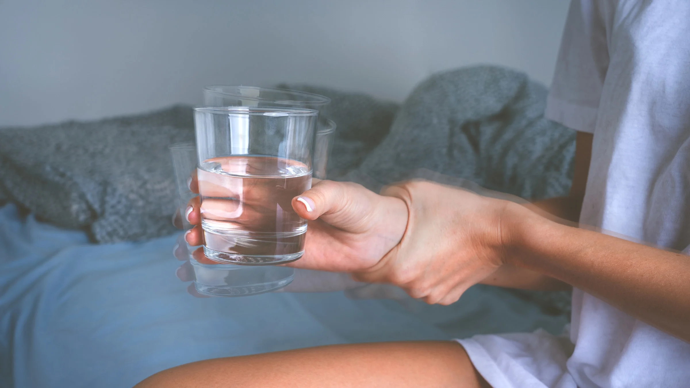 Shaky hands holding a glass of water.