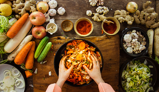 Top down view of a person prepping vegetables and cabbage for kimchi on a prep counter.
