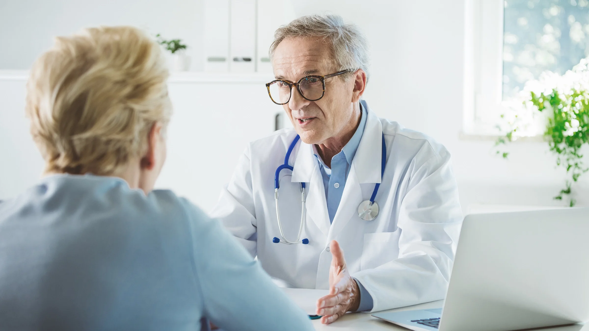 Back of an older woman's head as she is having a consultation with her provider. The focus is on the provider.