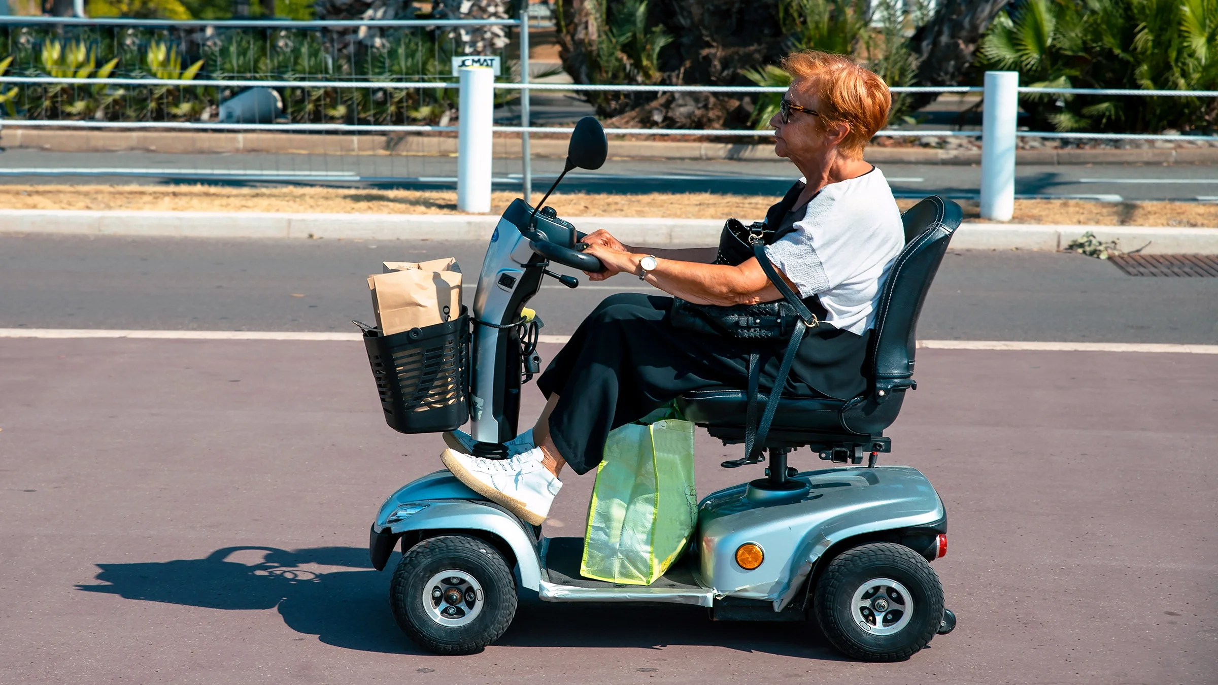 An older woman is driving a power scooter on the street.