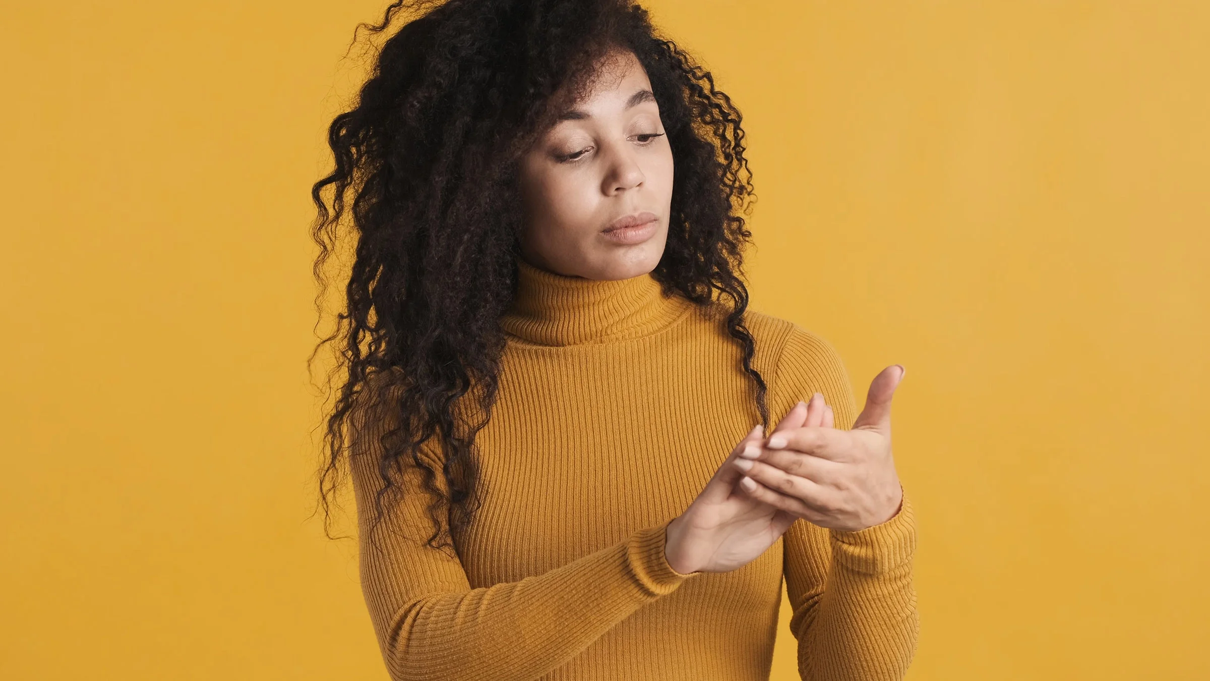 A woman looks at her nails. Conditions like eczema and psoriasis can cause nail pitting.