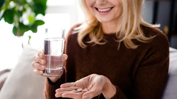 osteoporosis: woman taking medication with water 2086208354