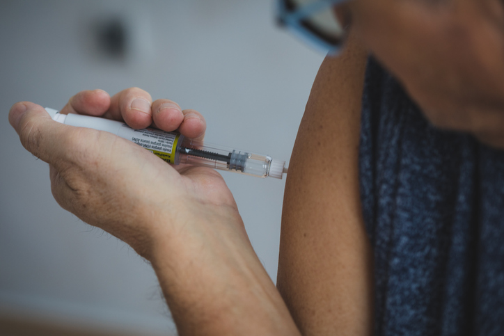 Close-up of a woman using an insulin pen injector on her arm.