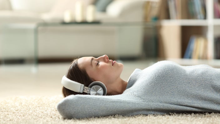 Woman laying down on carpet with headphones on