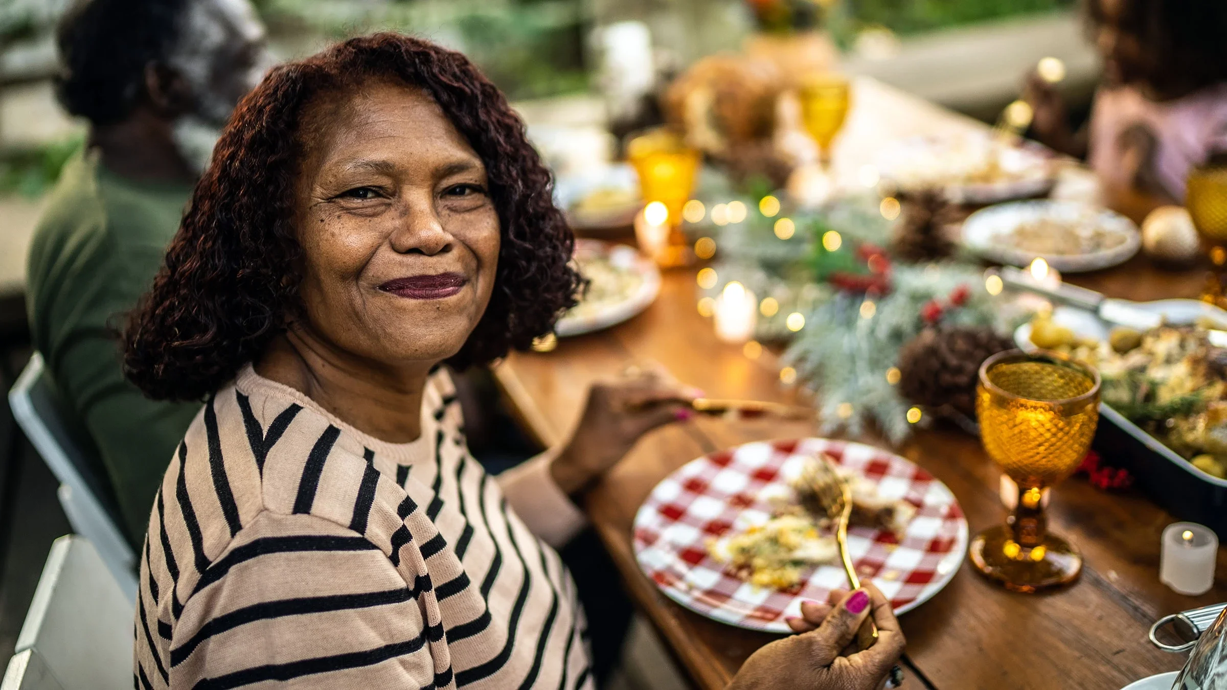 A senior woman smiles as she enjoys a holiday meal.