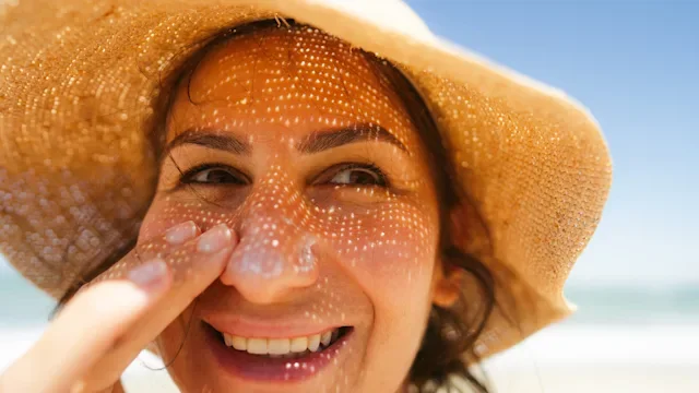 Dermatology: woman with sun hat applying sunscreen 2260015963