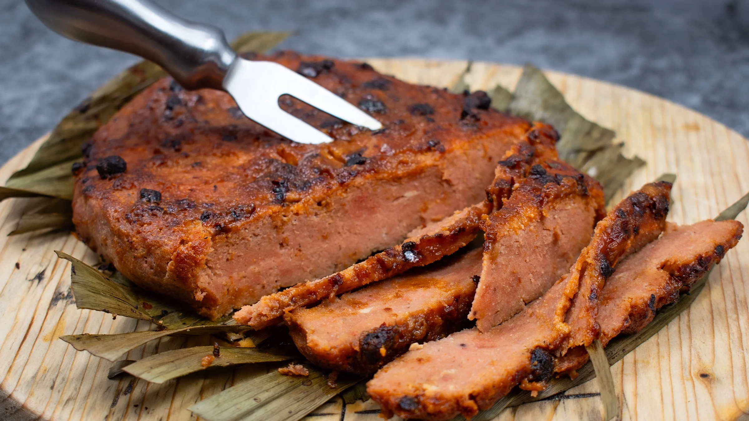 A piece of grilled seitan lies on a cutting board.