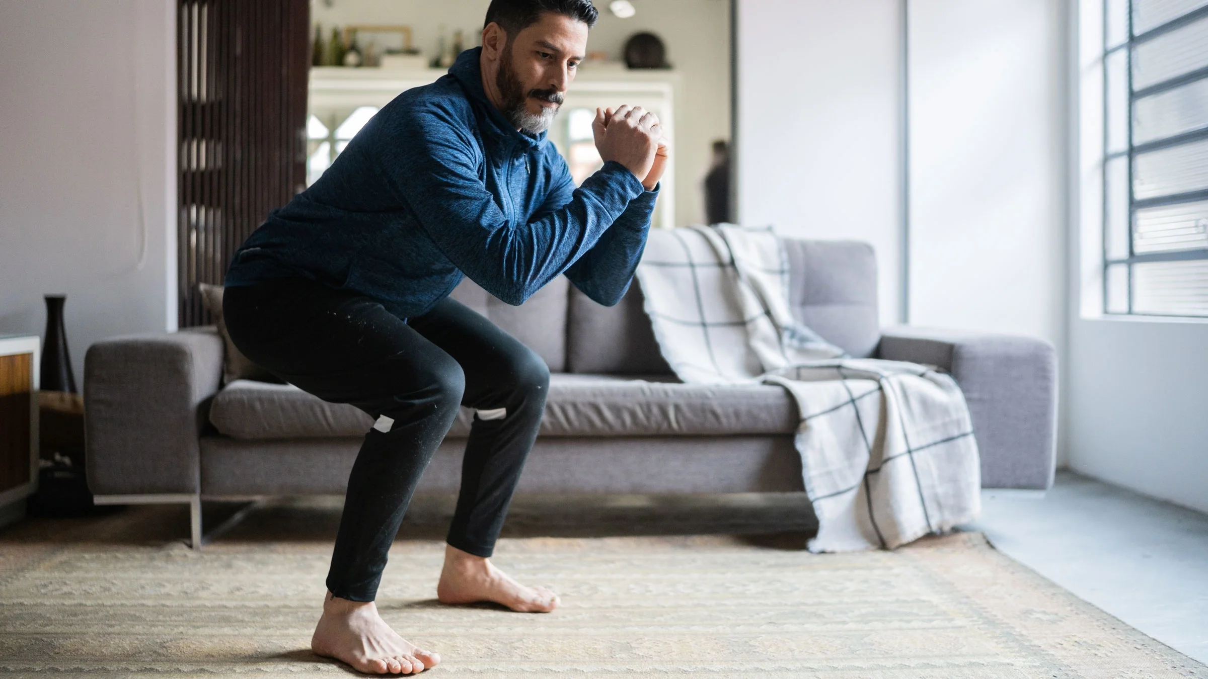Man doing squats in living room.