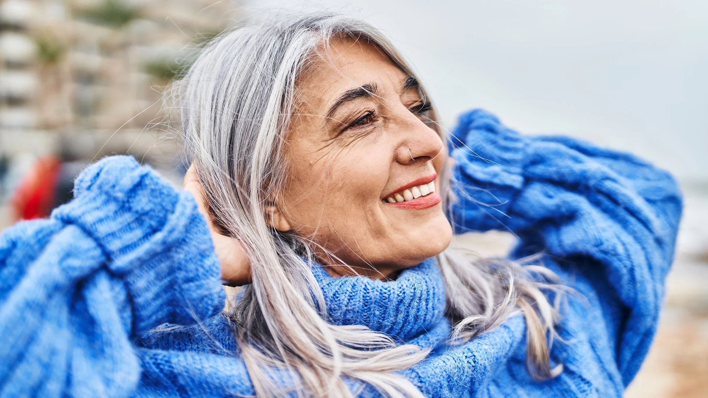A woman at the seaside smiles confidently as she puts her hands on her head.
AaronAmat/iStock via Getty Images Plus