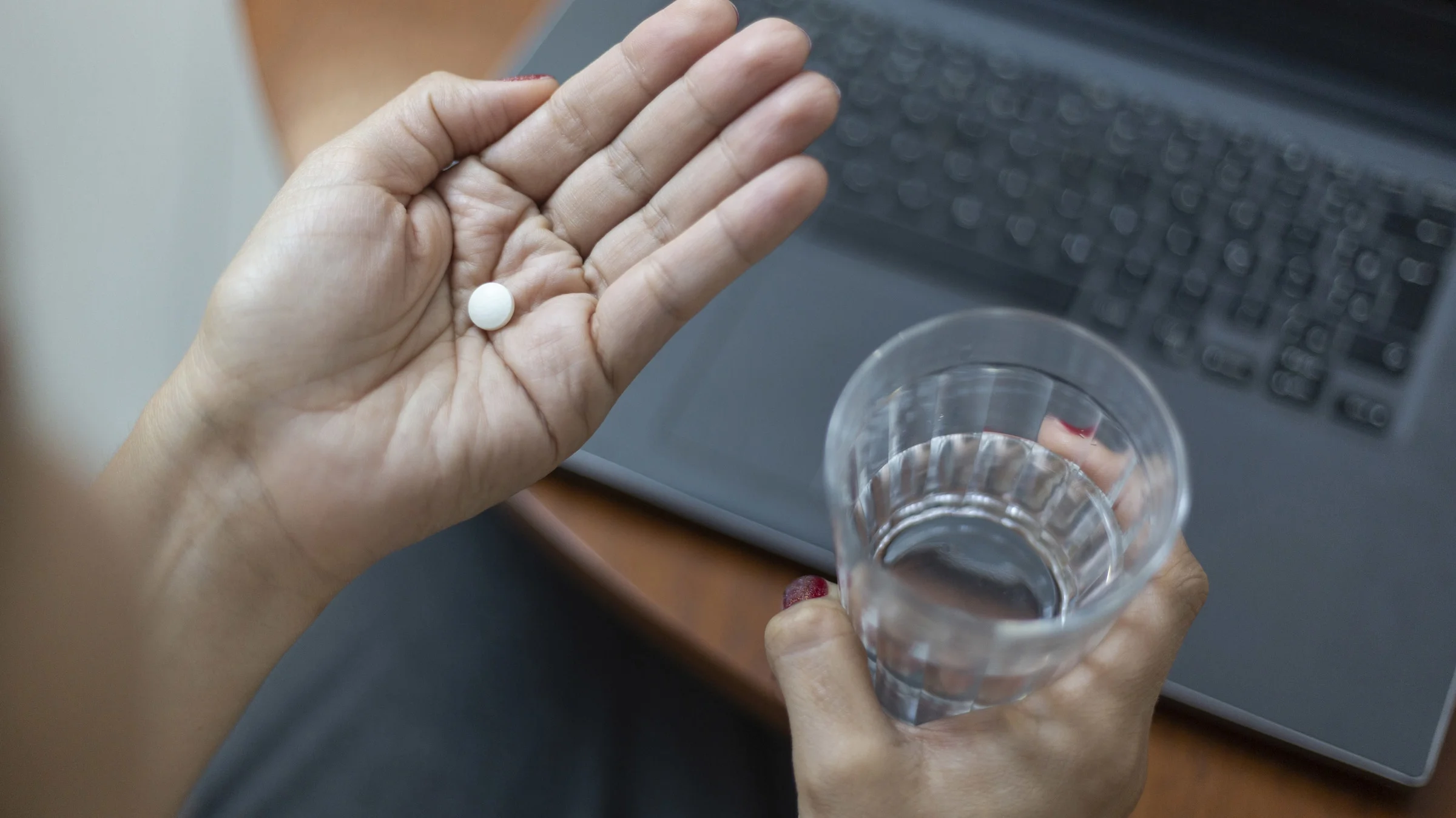 A woman holds pills in the palm of her hand.