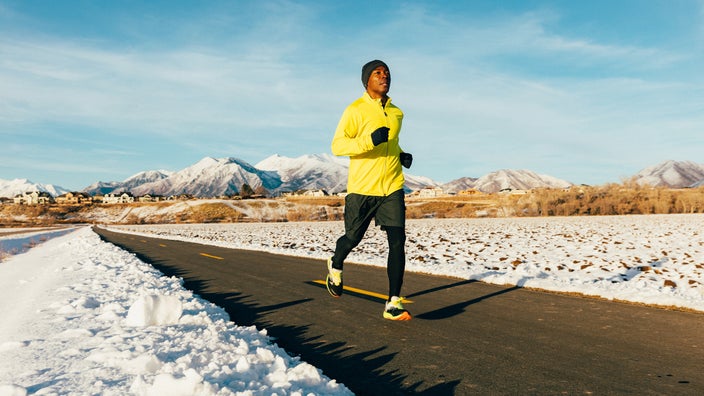A man goes for a run in the winter, surrounded by snow.