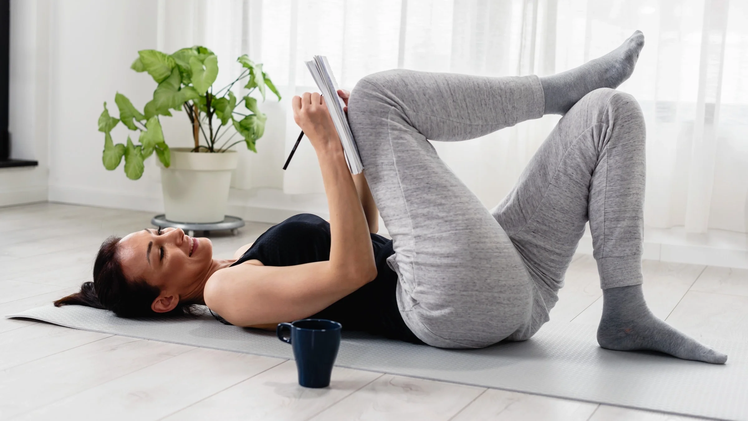 A person writing in a notebook on their yoga mat.
