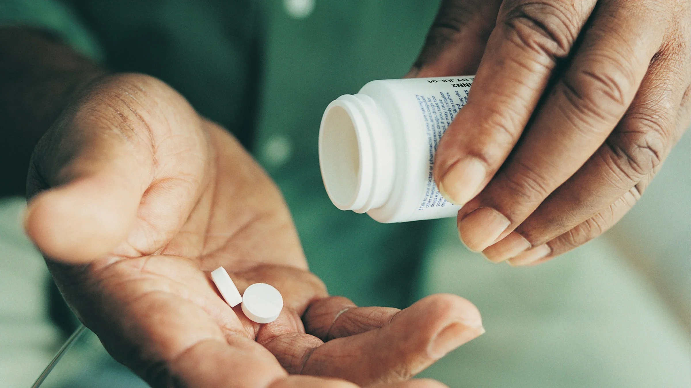 Close-up of older male pouring white round pills from container onto his hand.
Digital Vision/Photodisc via Getty Images