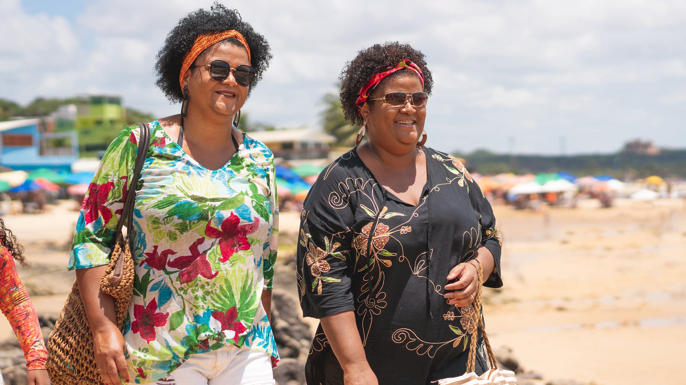 sisters walking on beach in tropical clothes-1183571717