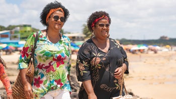 sisters walking on beach in tropical clothes-1183571717