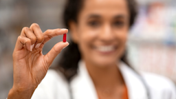 Close-up of long red pill being held by pharmacist.
Ridofranz/iStock via Getty Images
