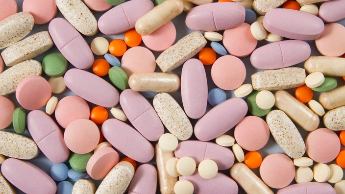 Close-up of a pile of various pills that are pastel in color. They range in size and shape too.