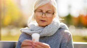 Health: Diclofenac: woman reading prescription bottle outside-1055560890