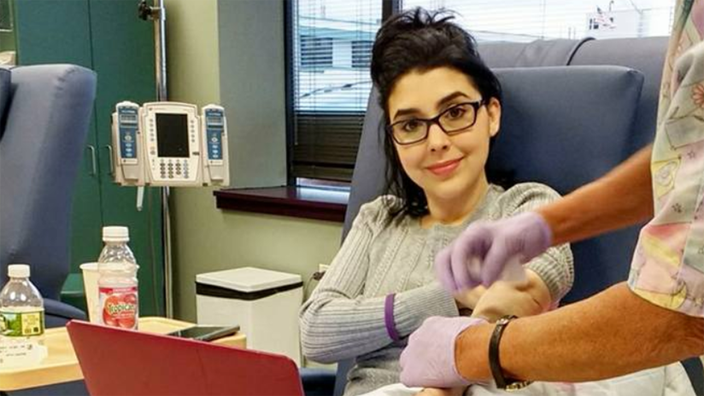 Marisa Zeppieri is pictured getting a medical treatment, while she works with her computer in her lap.