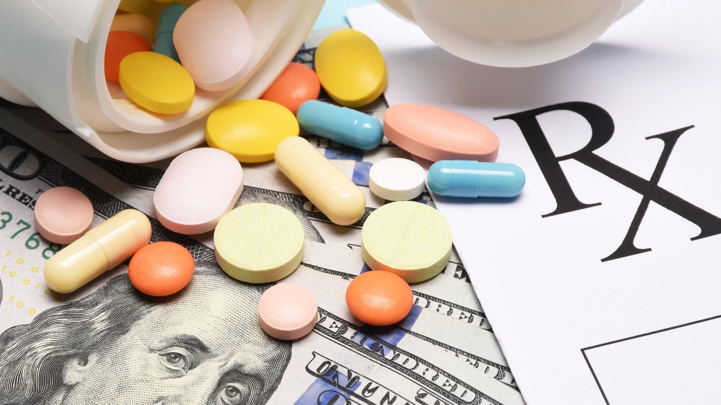Pills on top of dollar bills and a prescription pad.
s-cphoto/iStock via Getty Images Plus