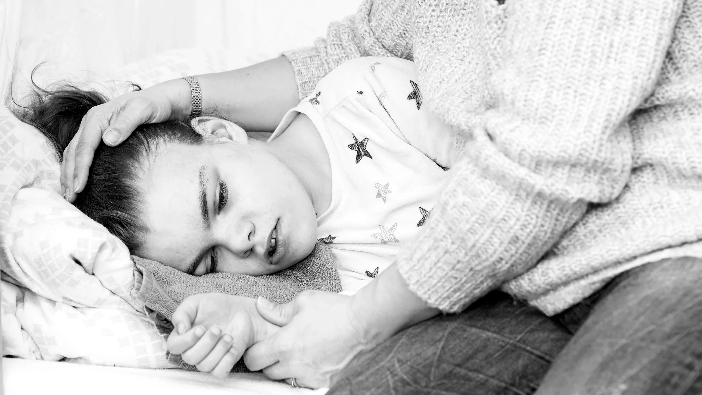 Black and white cropped image of a mother consoling their daughter after a seizure.