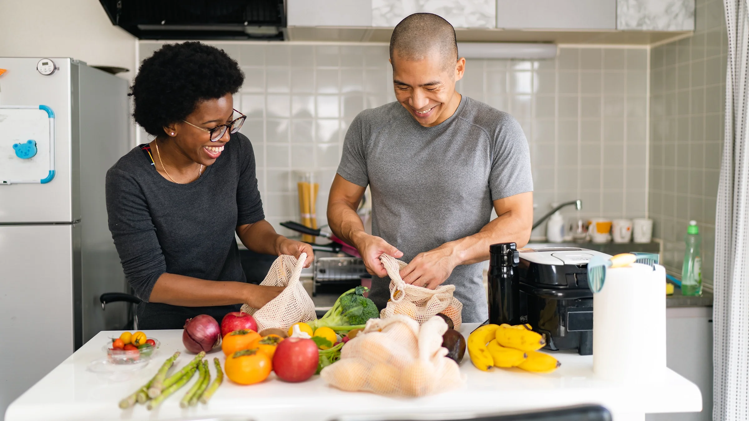 Couple emptying vegetables onto kitchen countertop