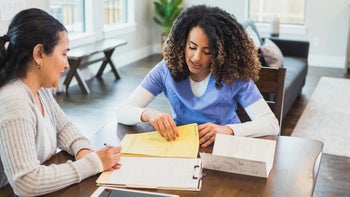 Health: Patient advocacy: woman filling out paperwork with nurse 1315220415