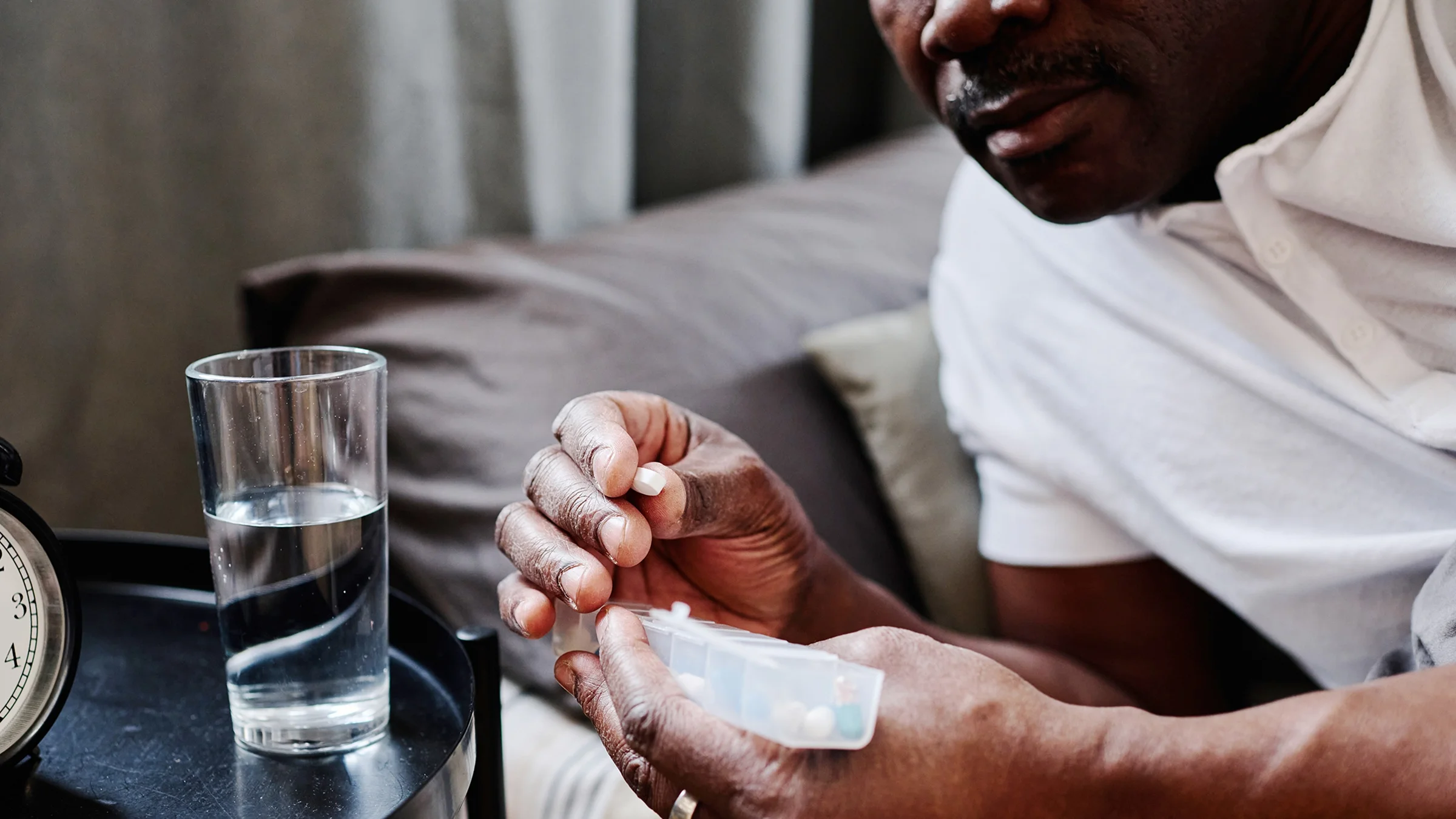 A man is taking medication from a pill organizer before bed.