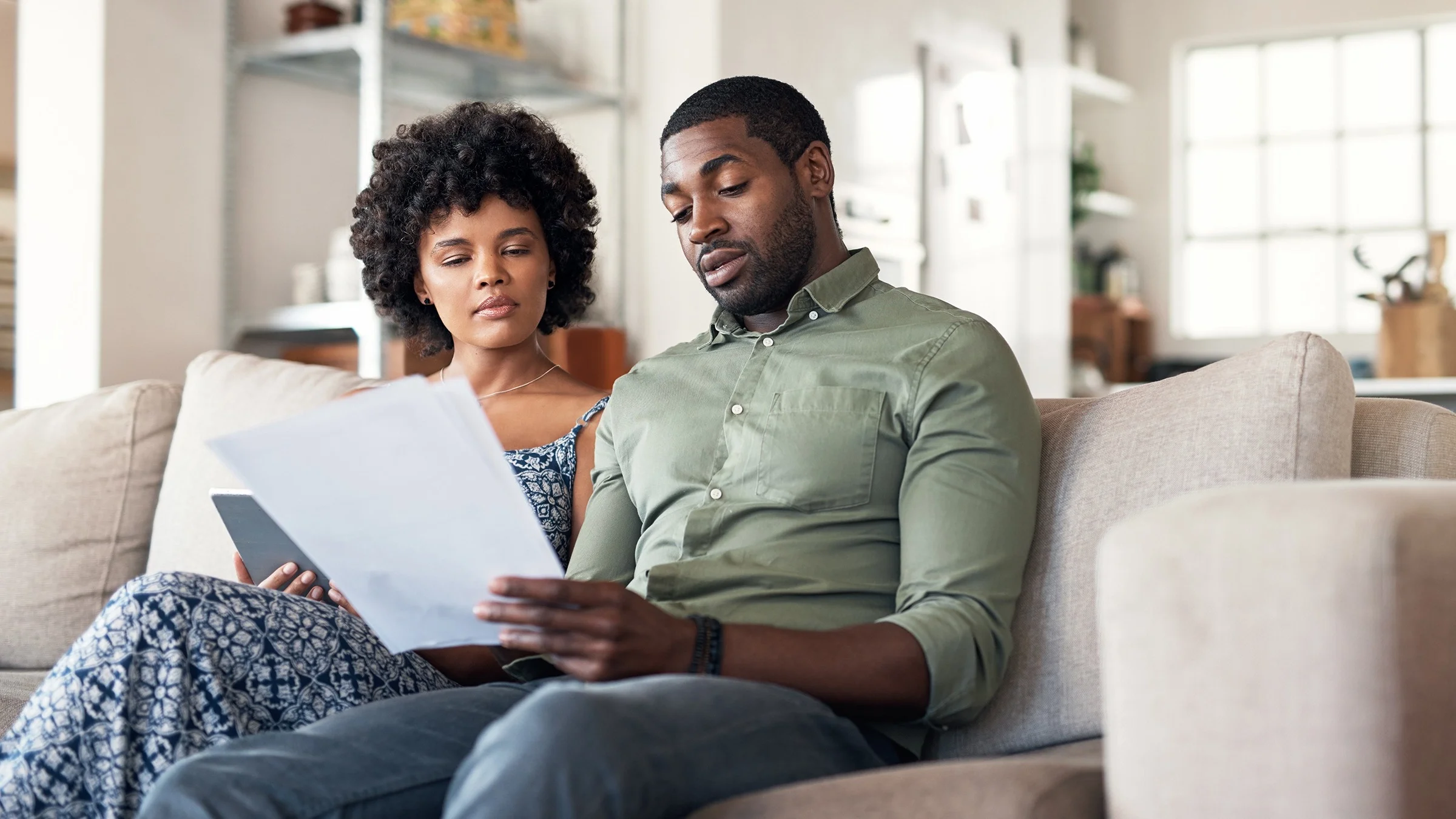Couple sitting on their couch reviewing paperwork together.