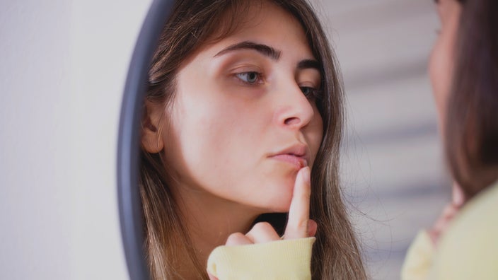 A person applying cream on a cold sore.