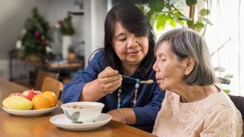 Senior Health: Caregiving: daugher feeding elderly mother 1294521542