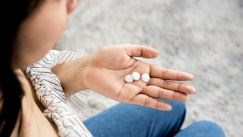 Health: Quetiapine: closeup woman taking three white pills-1310712022