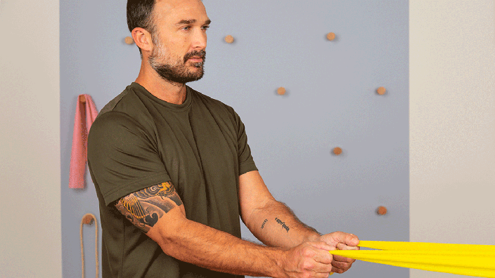 A man viewed in profile demonstrates scapular rows by pulling a resistance band with both arms.