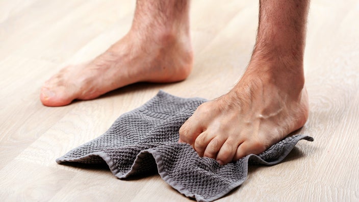 Close-up of a man’s foot as he does scrunch exercises with a towel.