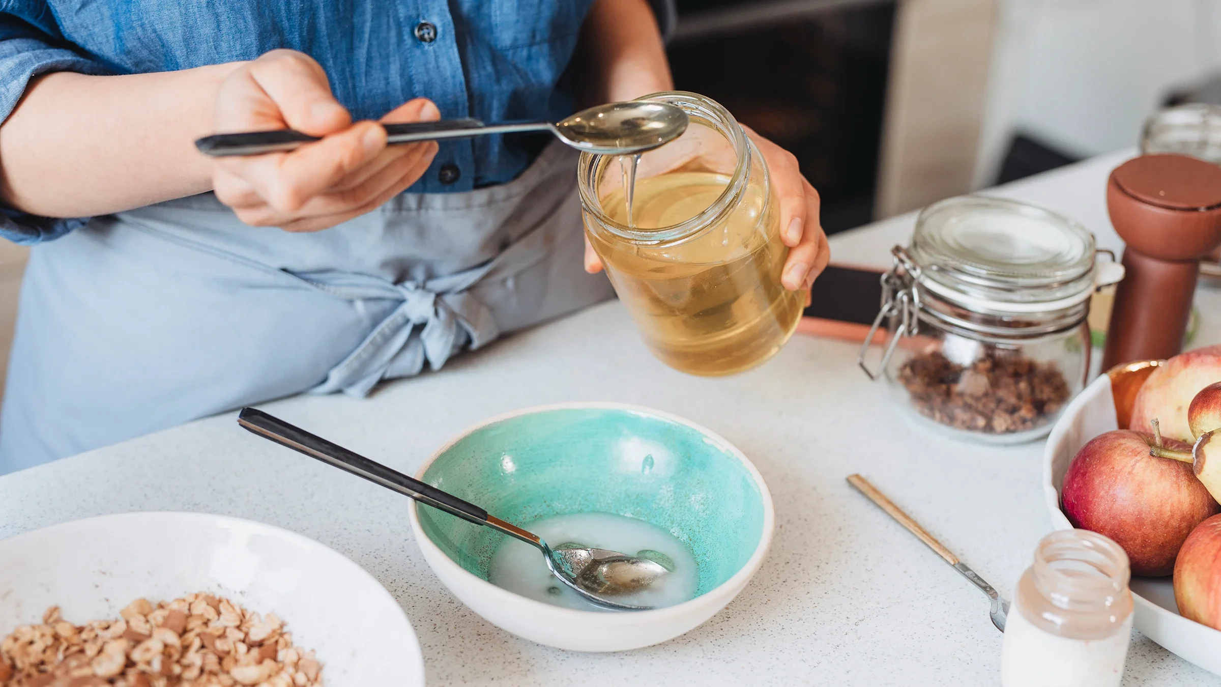 Cropped shot of a woman spooning honey into her morning granola.
FreshSplash/E+ via Getty Images